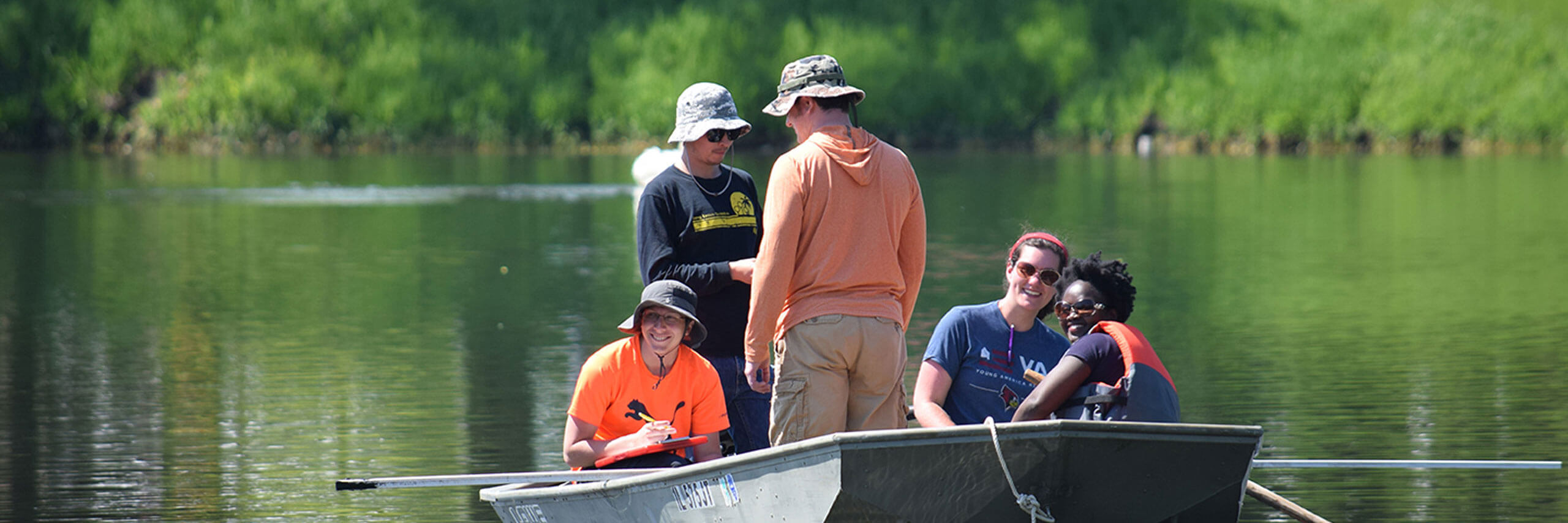 Several water center students in a boat taking water samples from a lake.